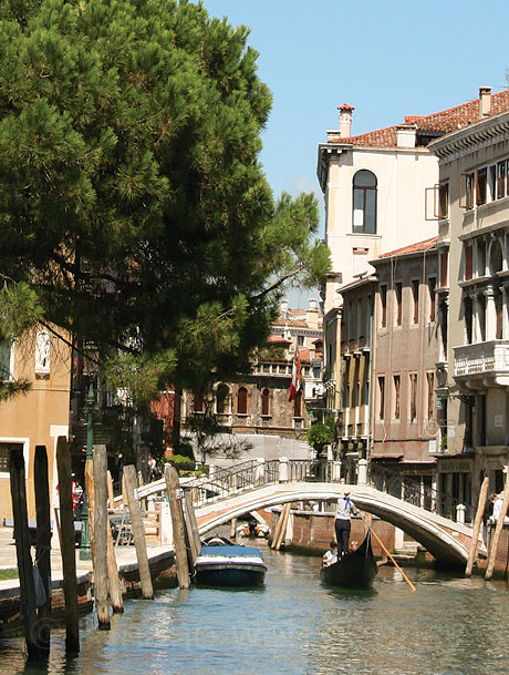 Gondolier trecand pe sub o punte pe un rio din venetia foto
